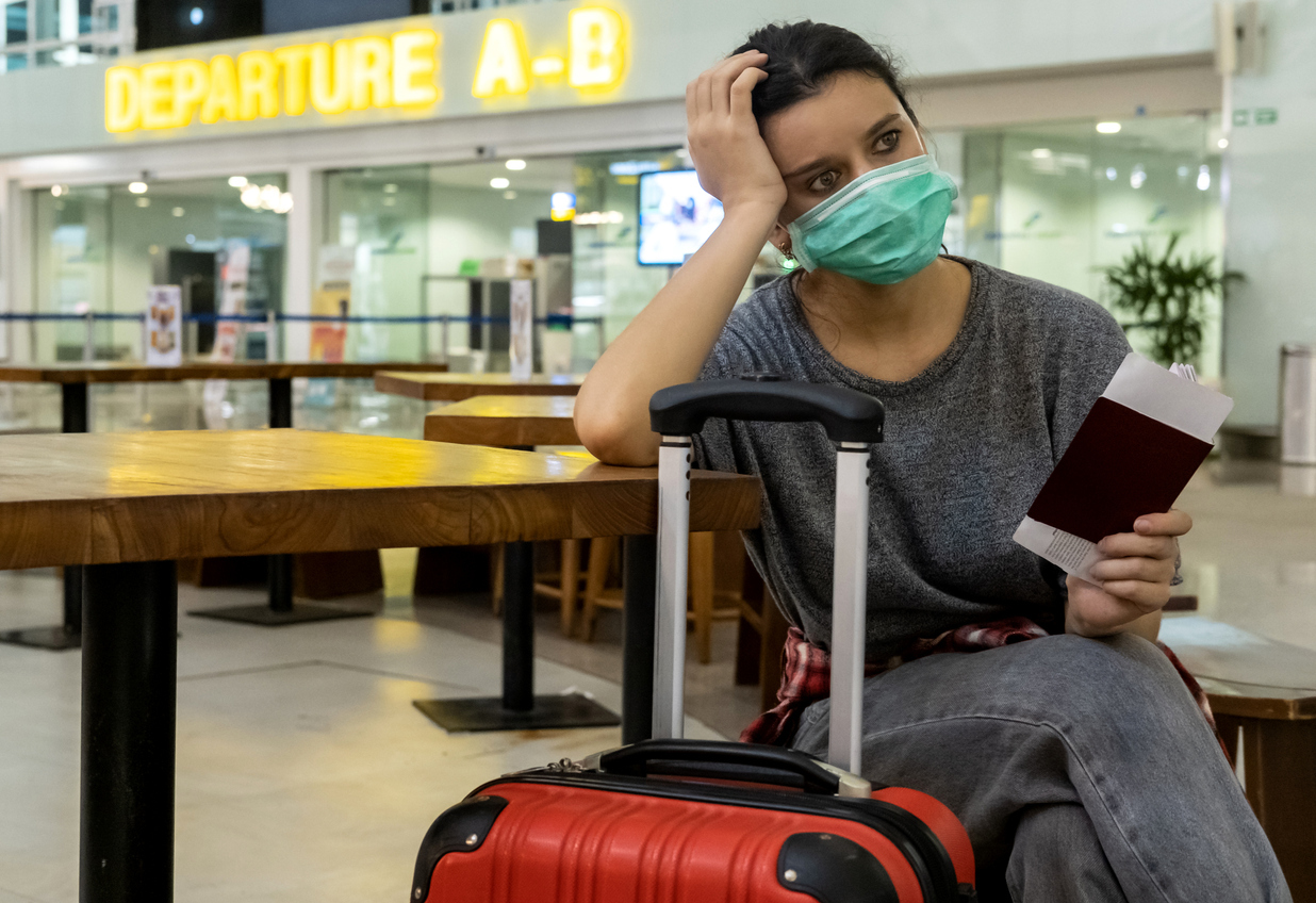 A female traveler sitting with her luggage looking distressed