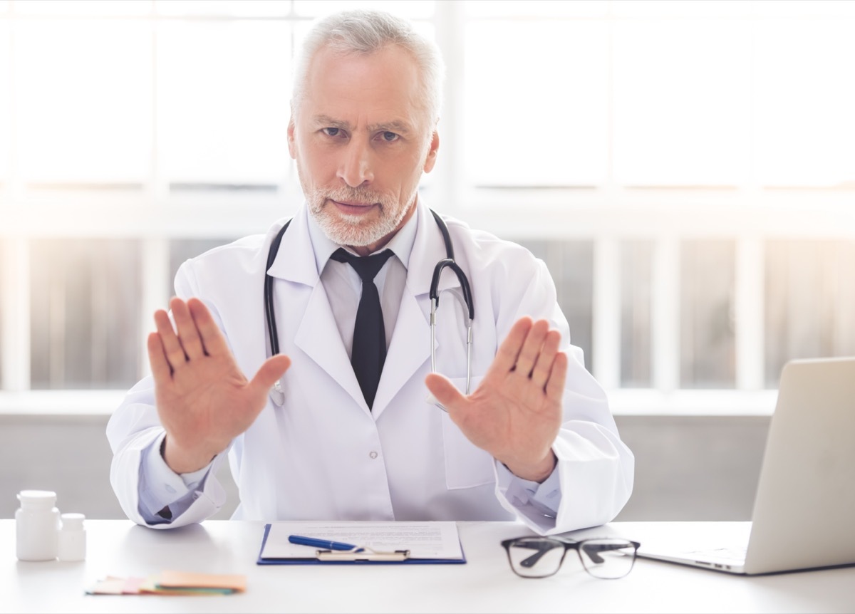 doctor in white coat is showing palms