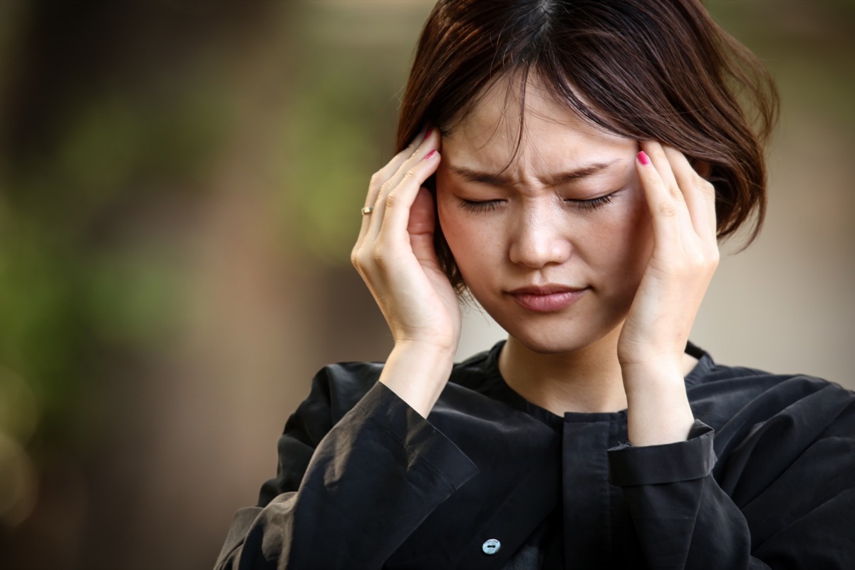 young woman rubbing her temples looking like she is in pain