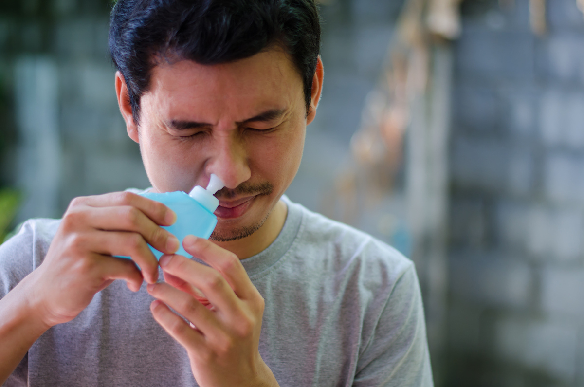 asian man uses saline to clean sinuses