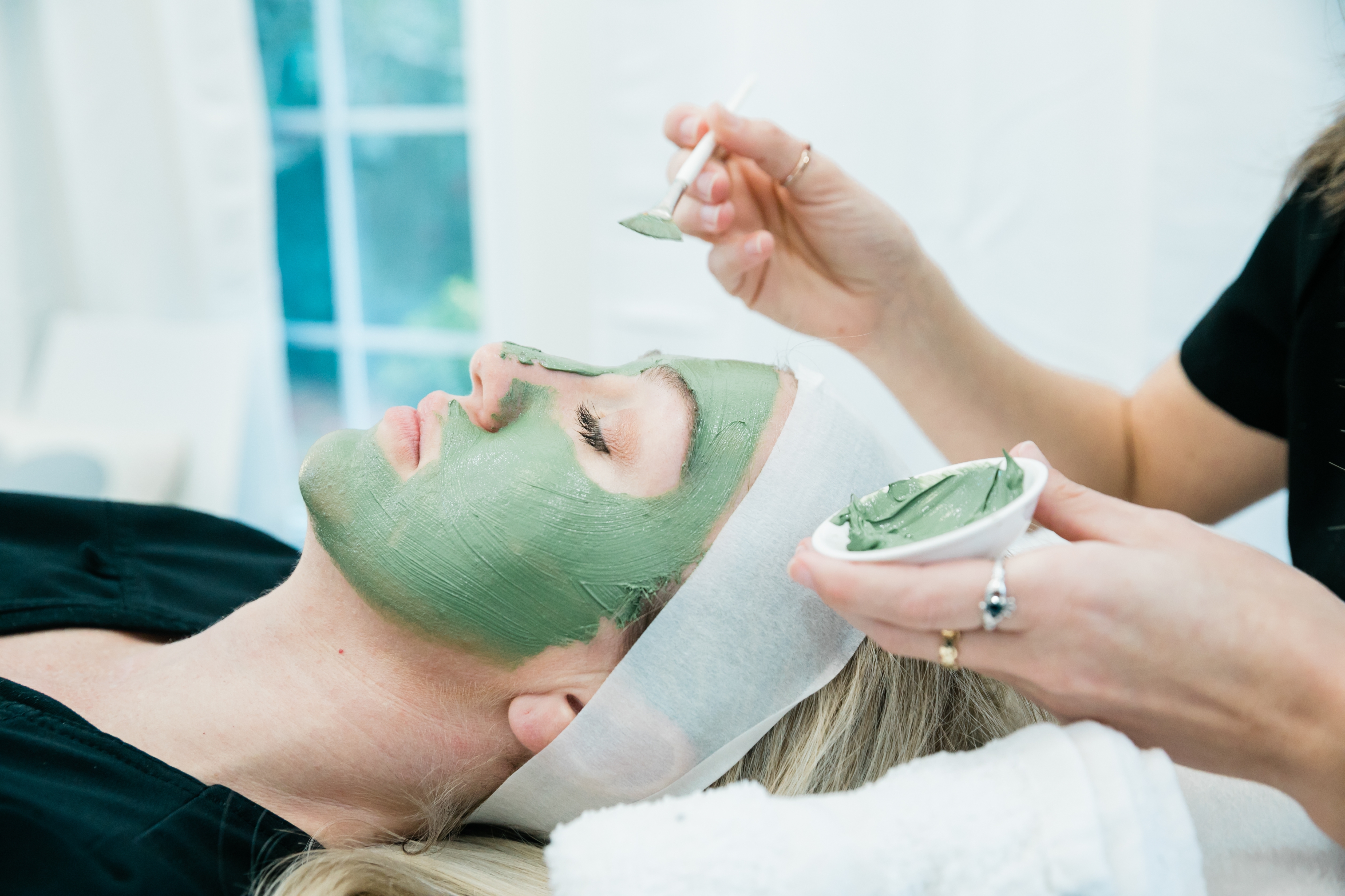 Woman applying green tea face mask for skincare