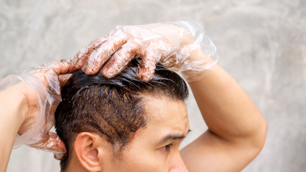 Asian men dye his hair color on a gray background. - Image