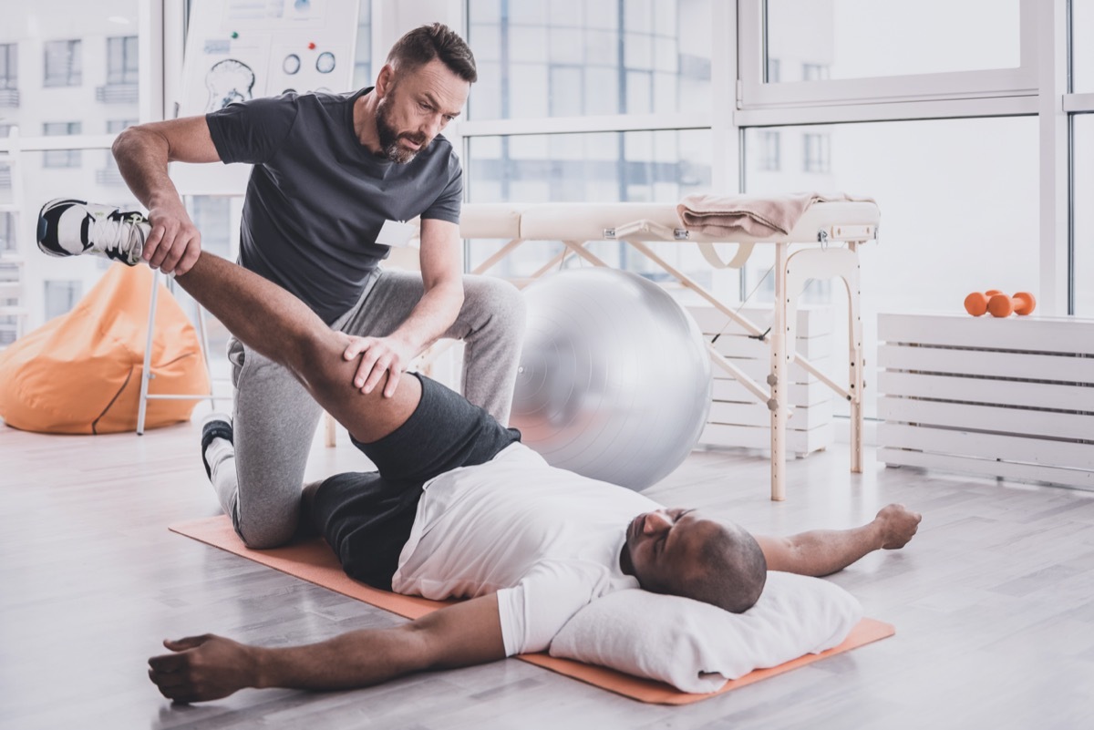 therapist bowing head while examining his patient