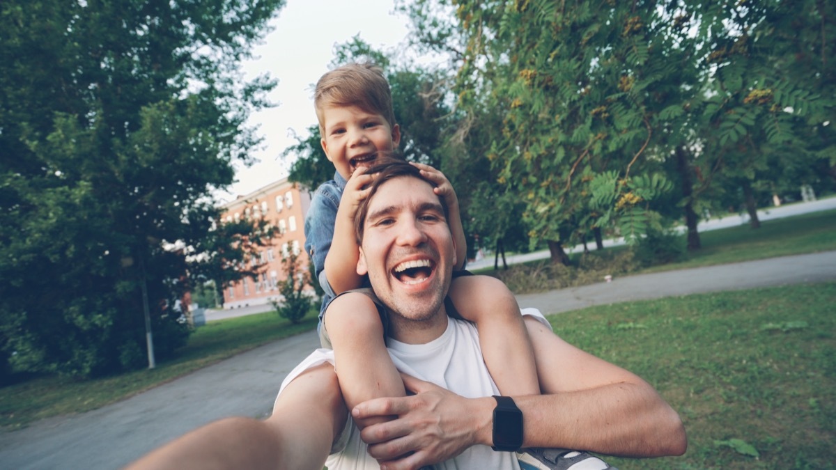 father giving son a shoulder ride taking a selfie