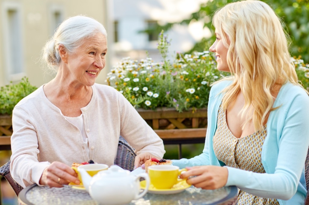 Grandma, older mom sitting down with her grown adult daughter for a drink