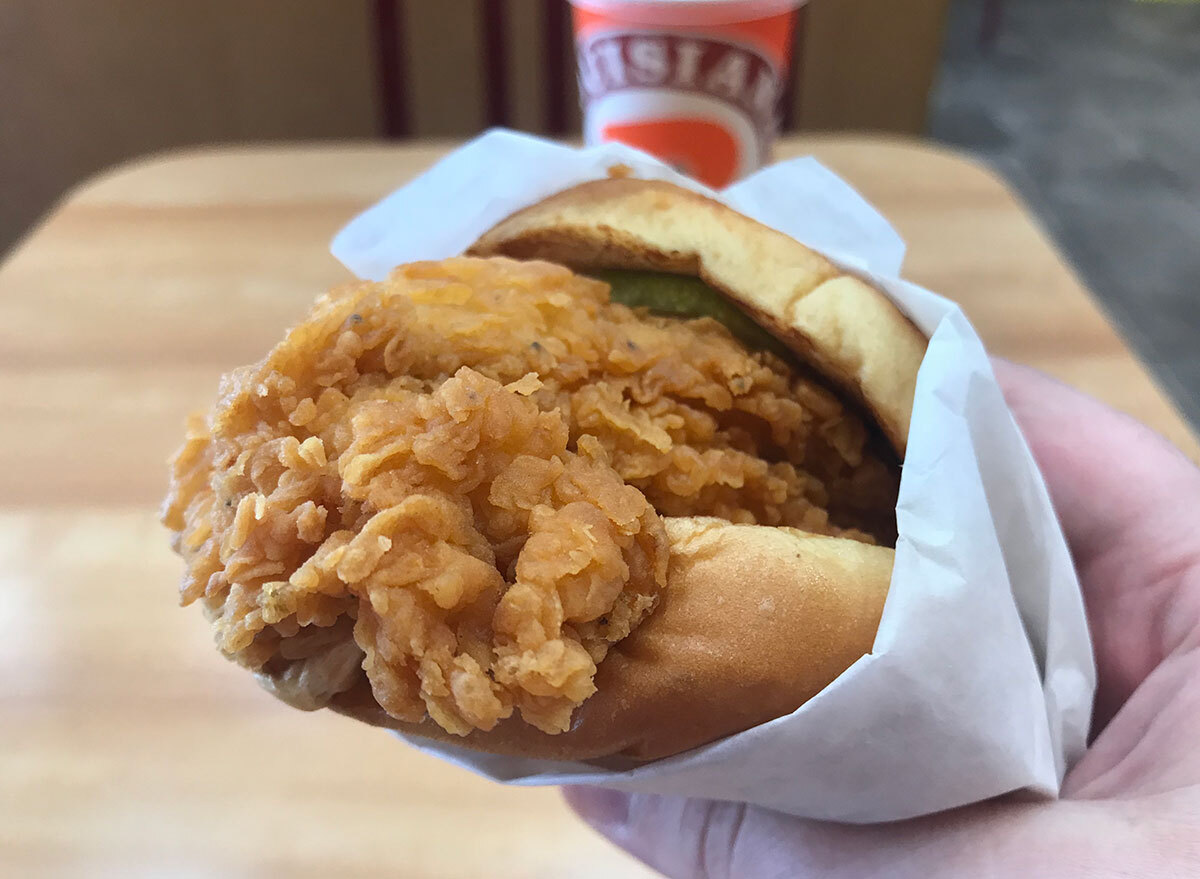 popeyes chicken sandwich with drink in background