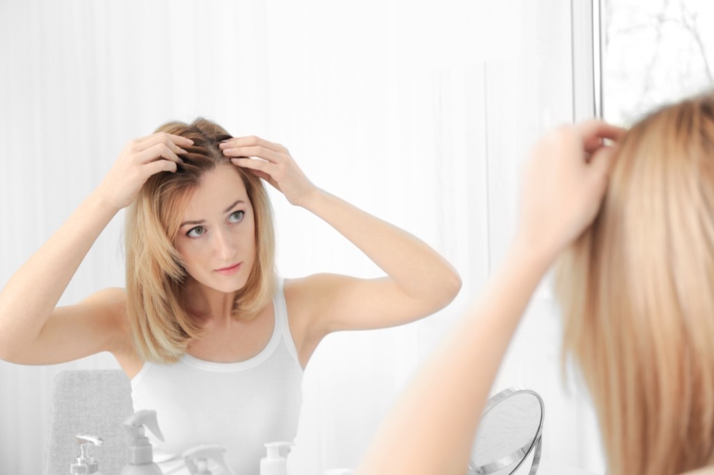 woman looking at the roots of her hair, ways your body changes after 40