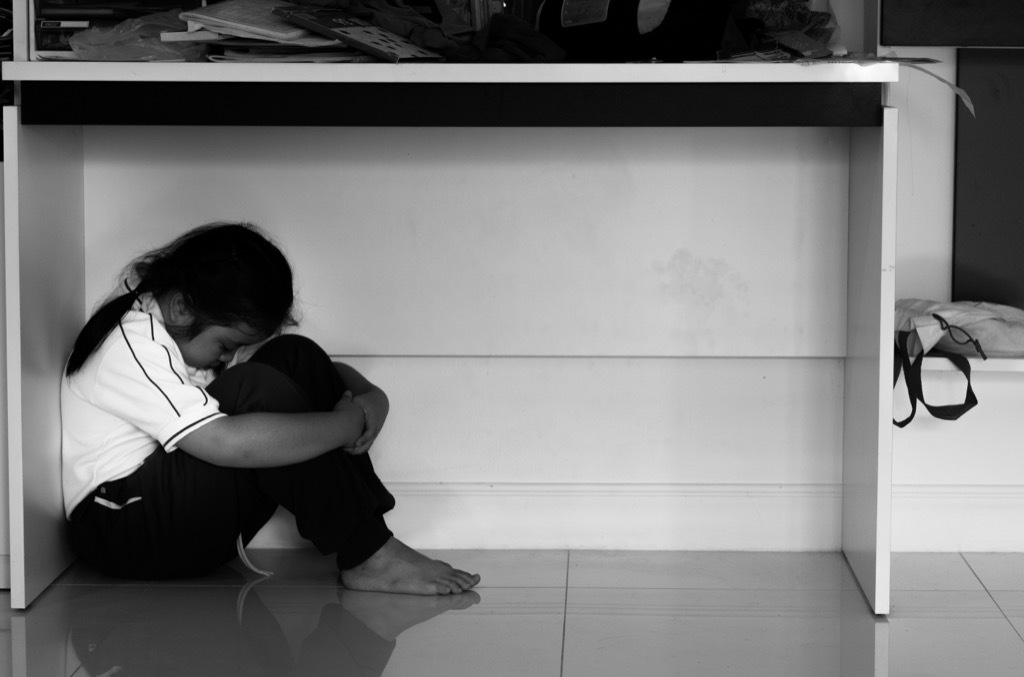 kid hiding under desk