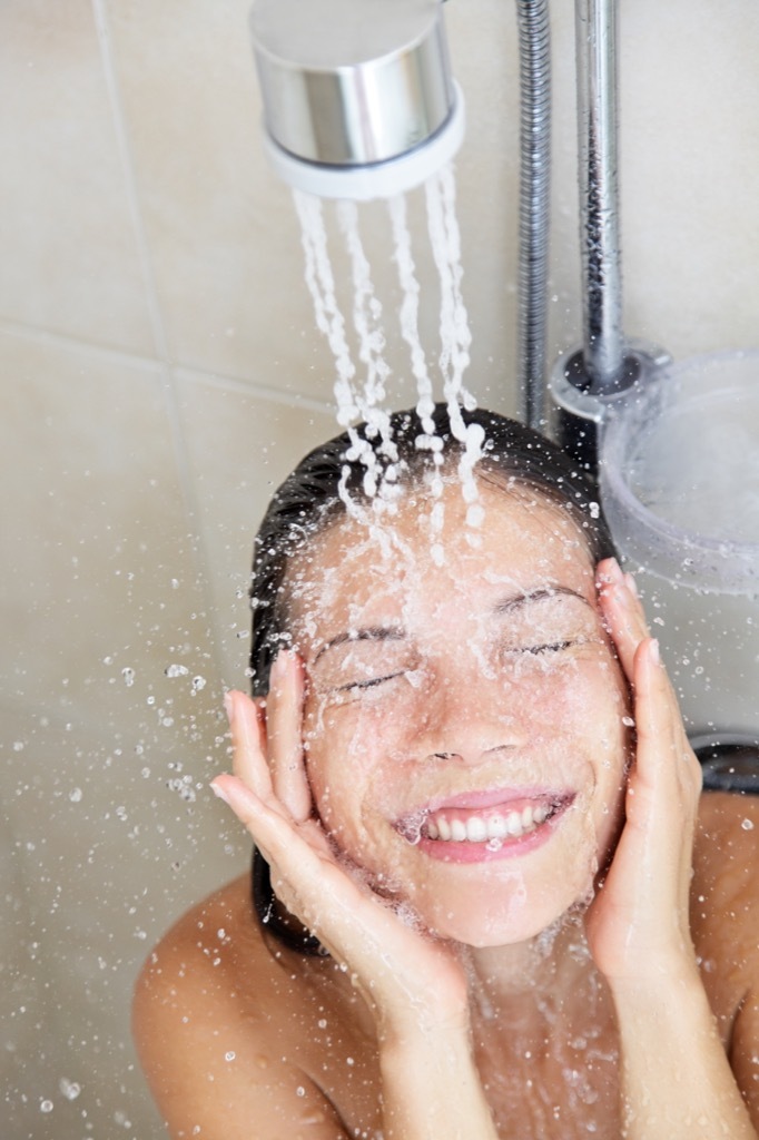 Woman washing her face in the shower.