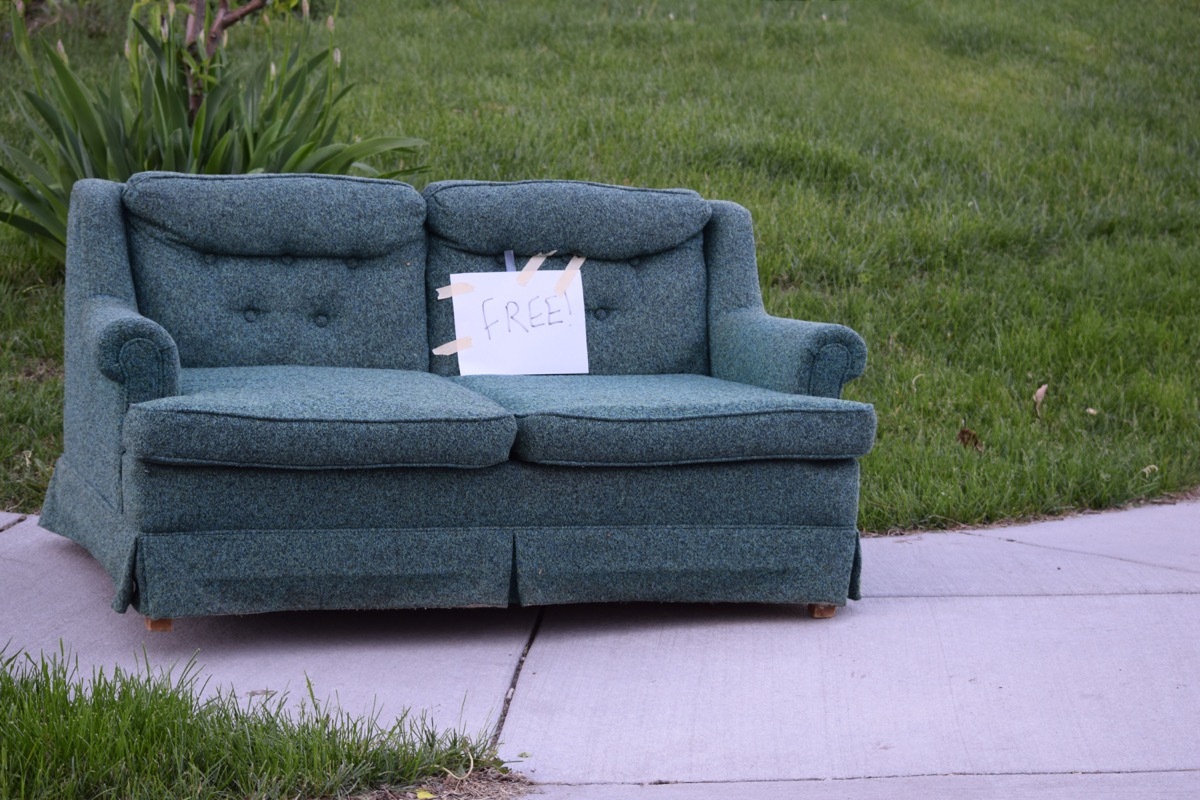 sofa placed on the sidewalk with a sign marking it free for pick up