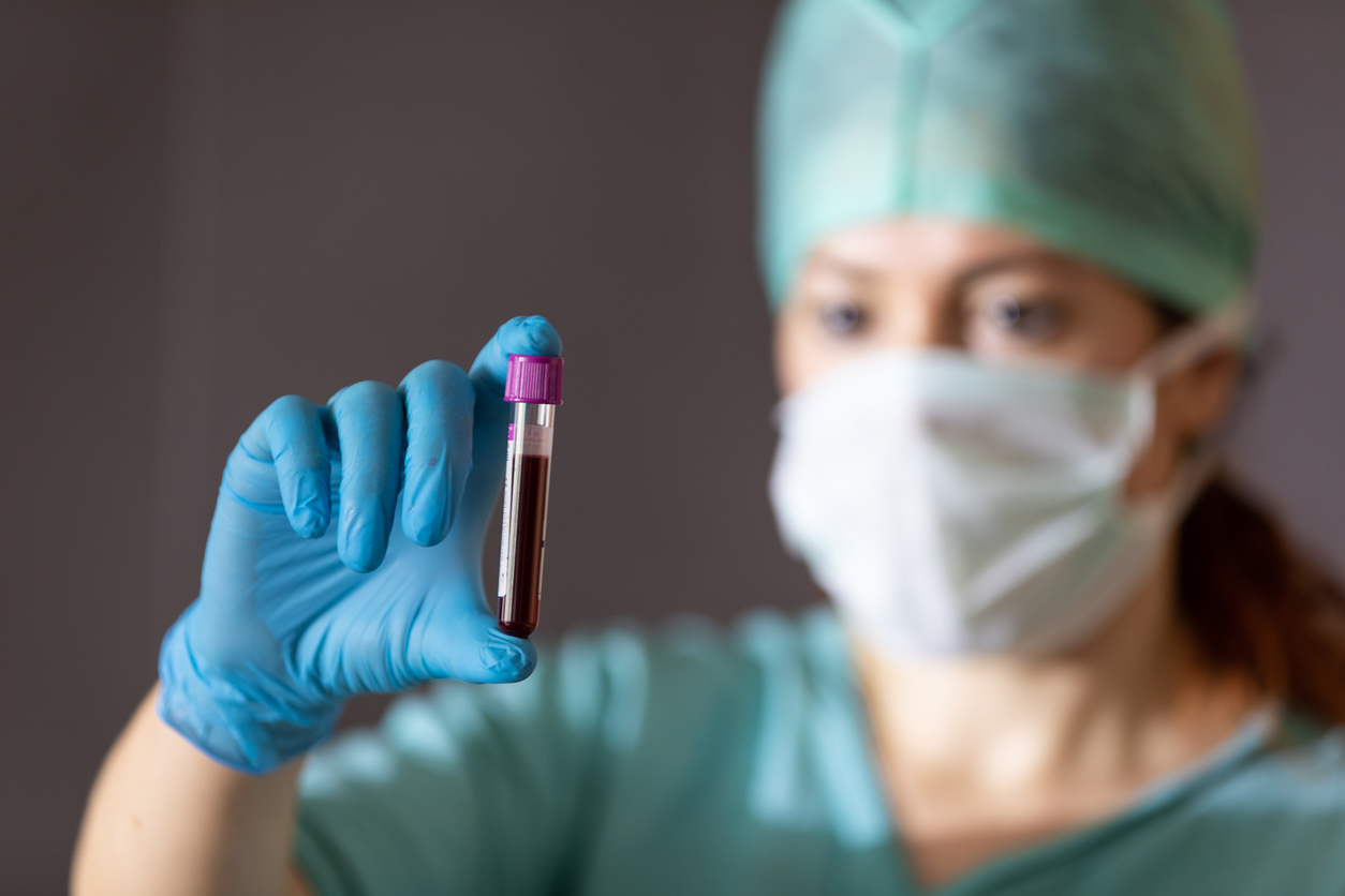 A female doctor holds up a test vile of blood