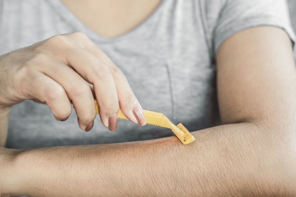 woman shaving her arm air with a razor