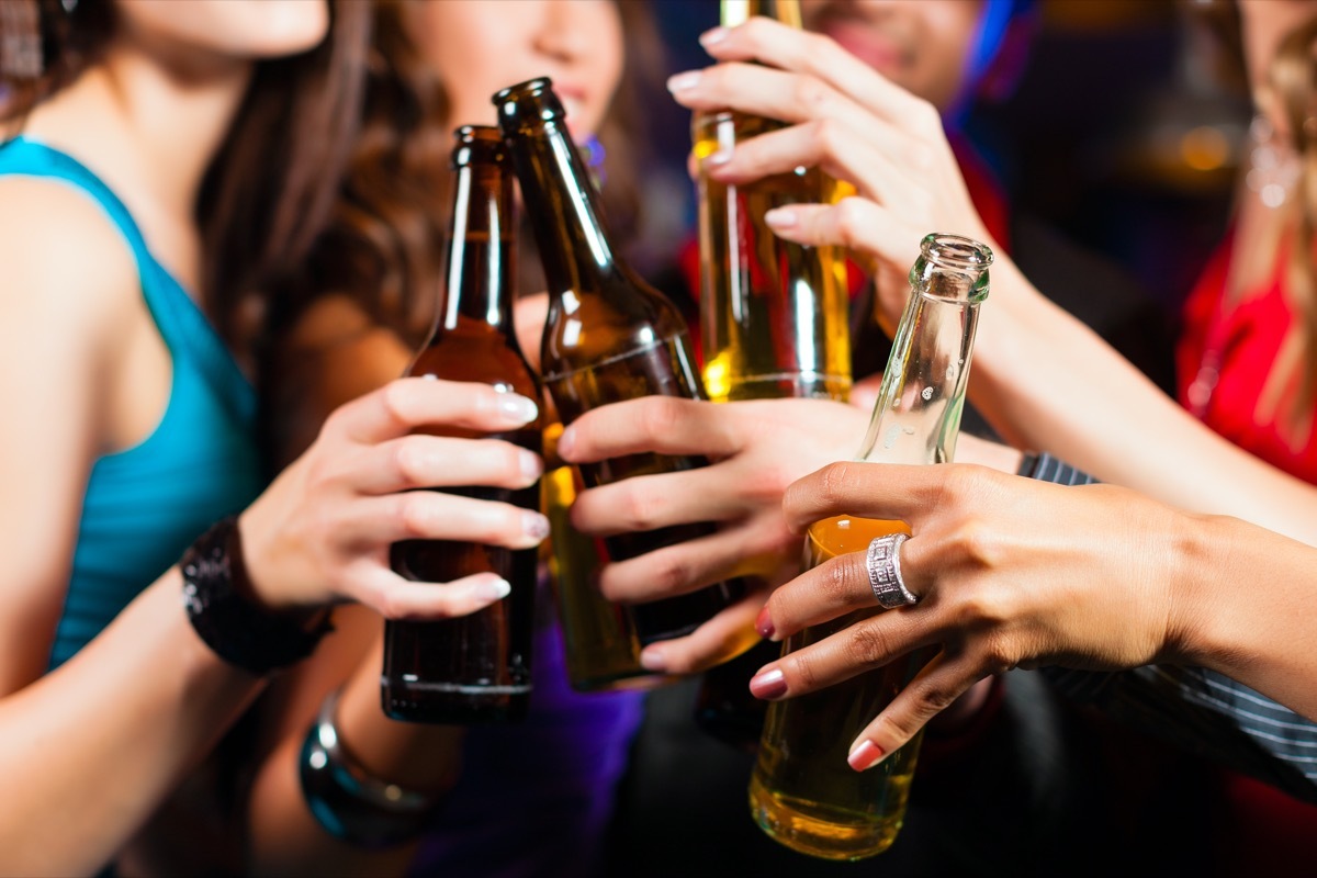 Group of party people - men and women - drinking beer in a pub or bar