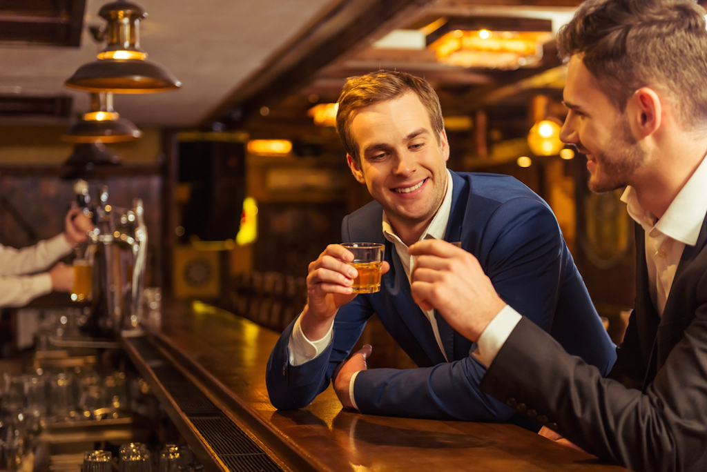 two businessmen drink at a bar