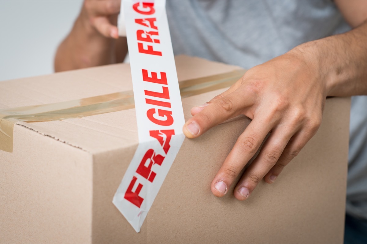 Close up Of A Man Packing Cardboard Box With Sellotape