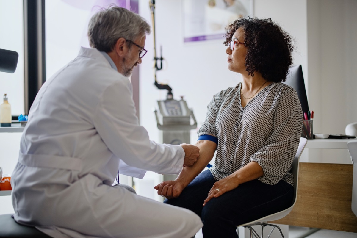 A woman getting her blood pressure taken by a male doctor