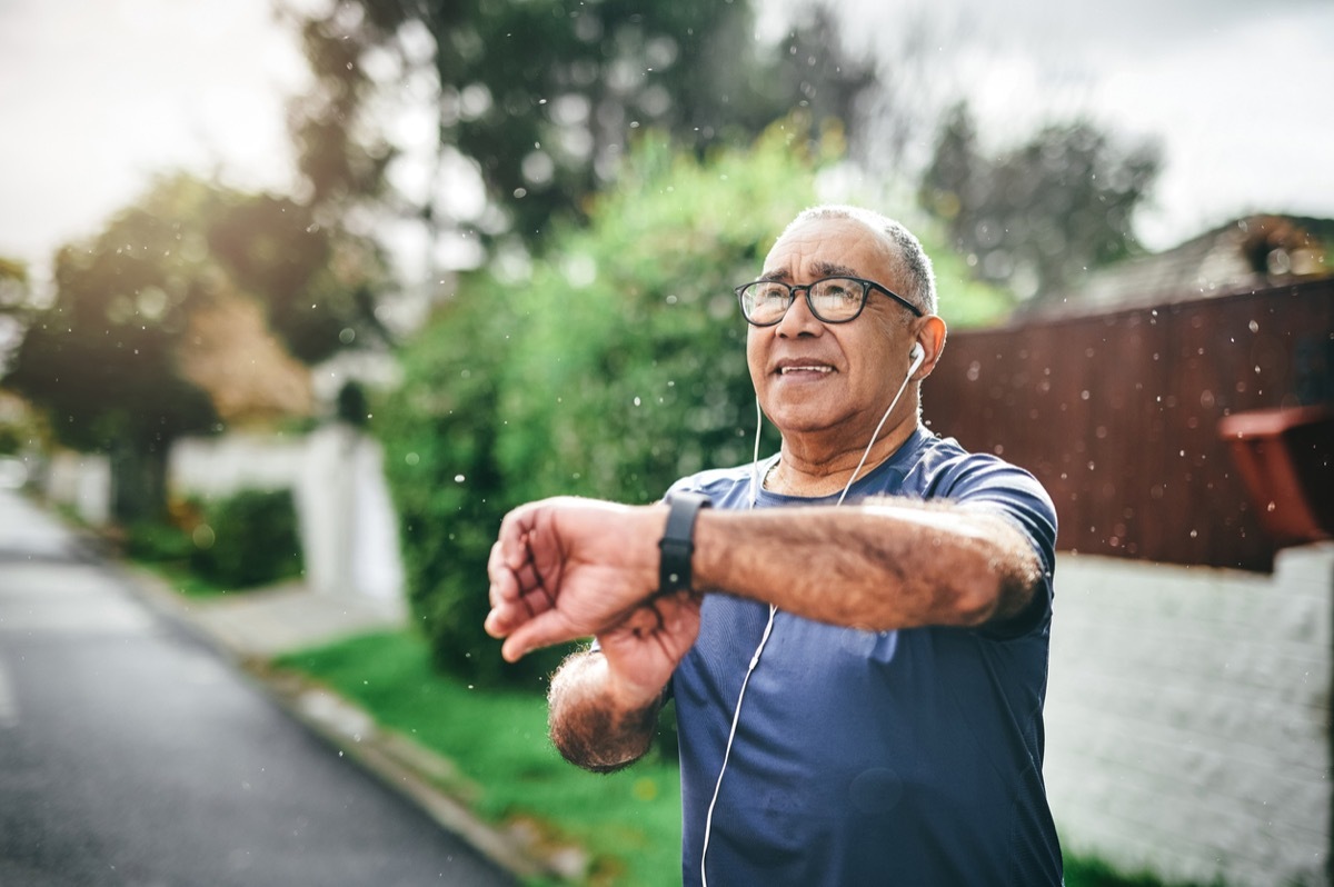 Shot of a senior man standing alone outside and checking his watch after going for a run