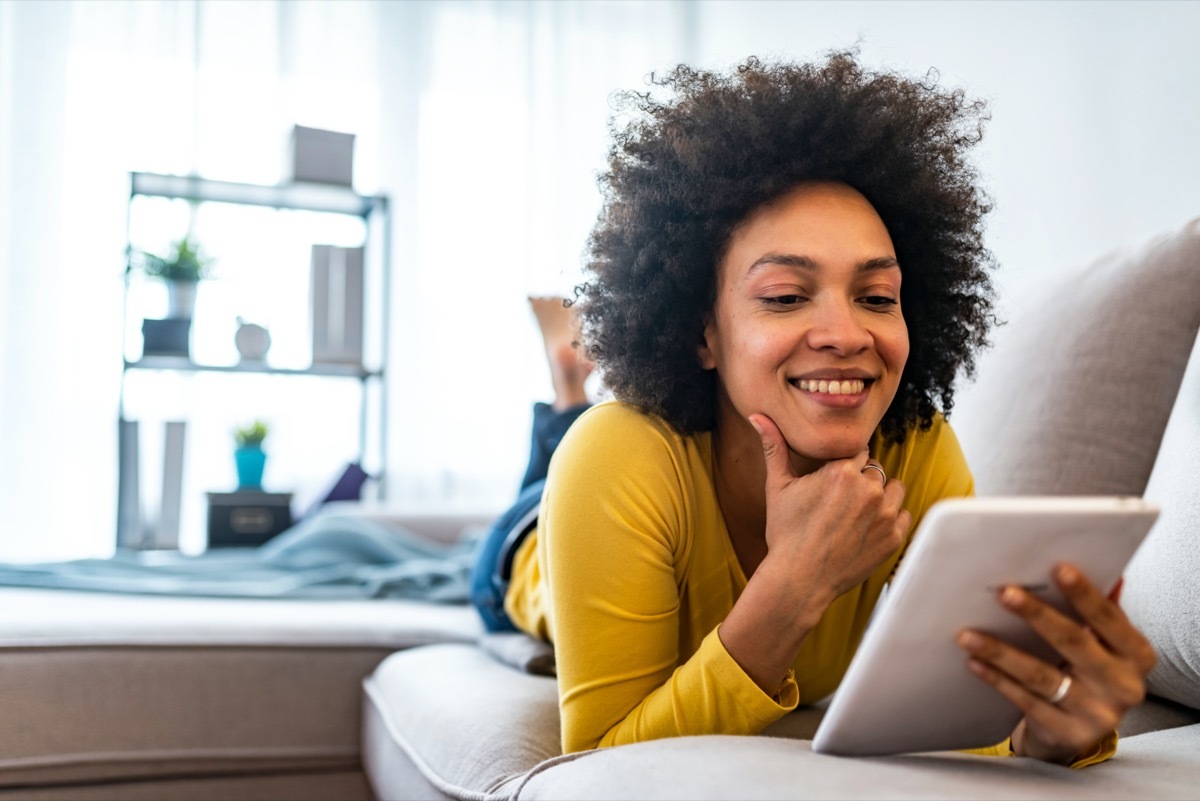 Woman laying on couch and reading iPad