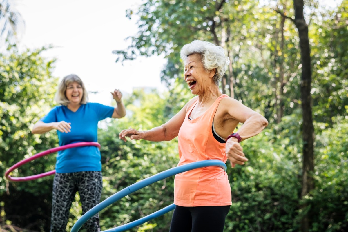 Asian woman exercising outside with a hula hoop