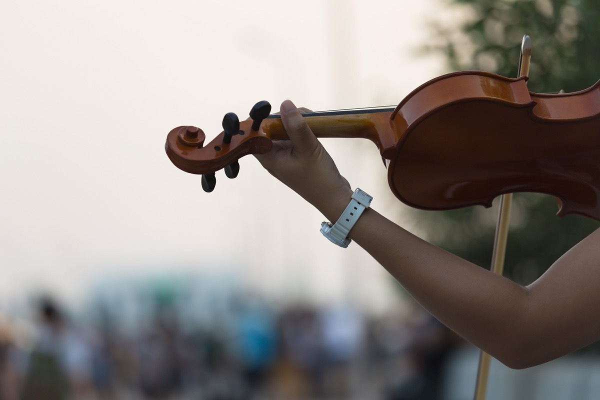 woman playing a fiddle in front of a large audience