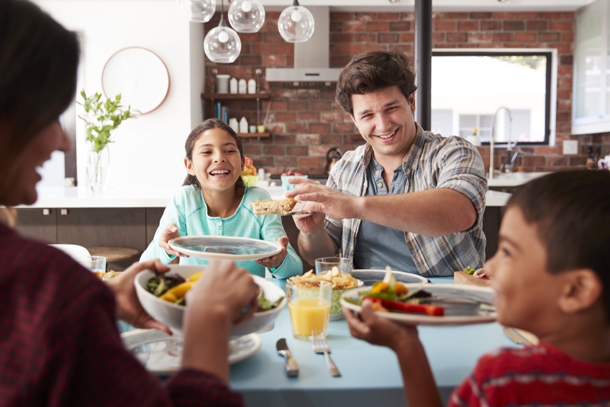 Family Enjoying Meal Around Table At Home Together