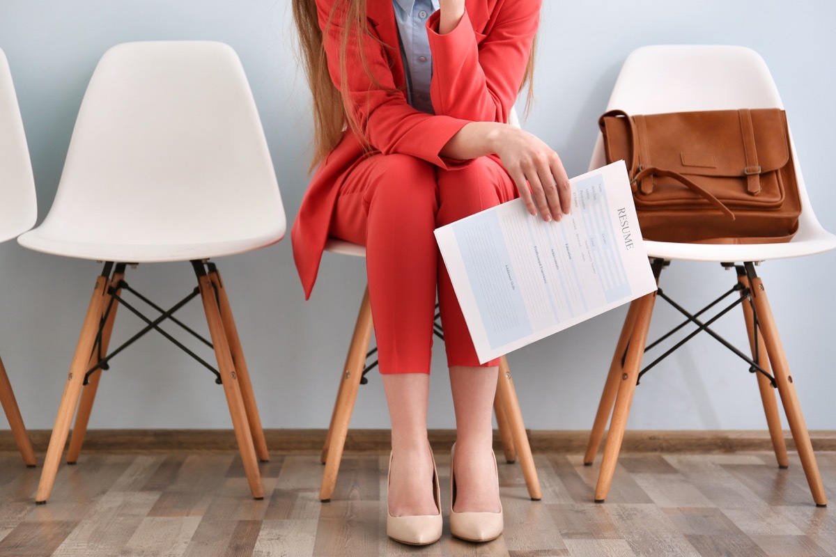 Cropped shot of a young woman in a red suit waiting for an interview, holding her resume