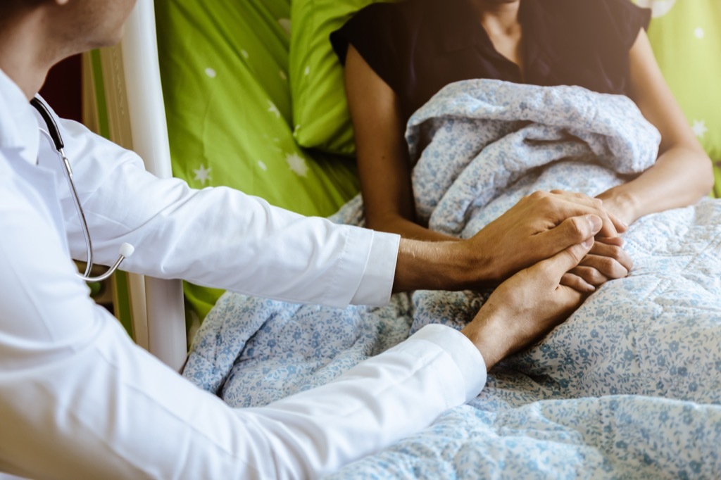 doctor holding a patients hands on a hospital bed