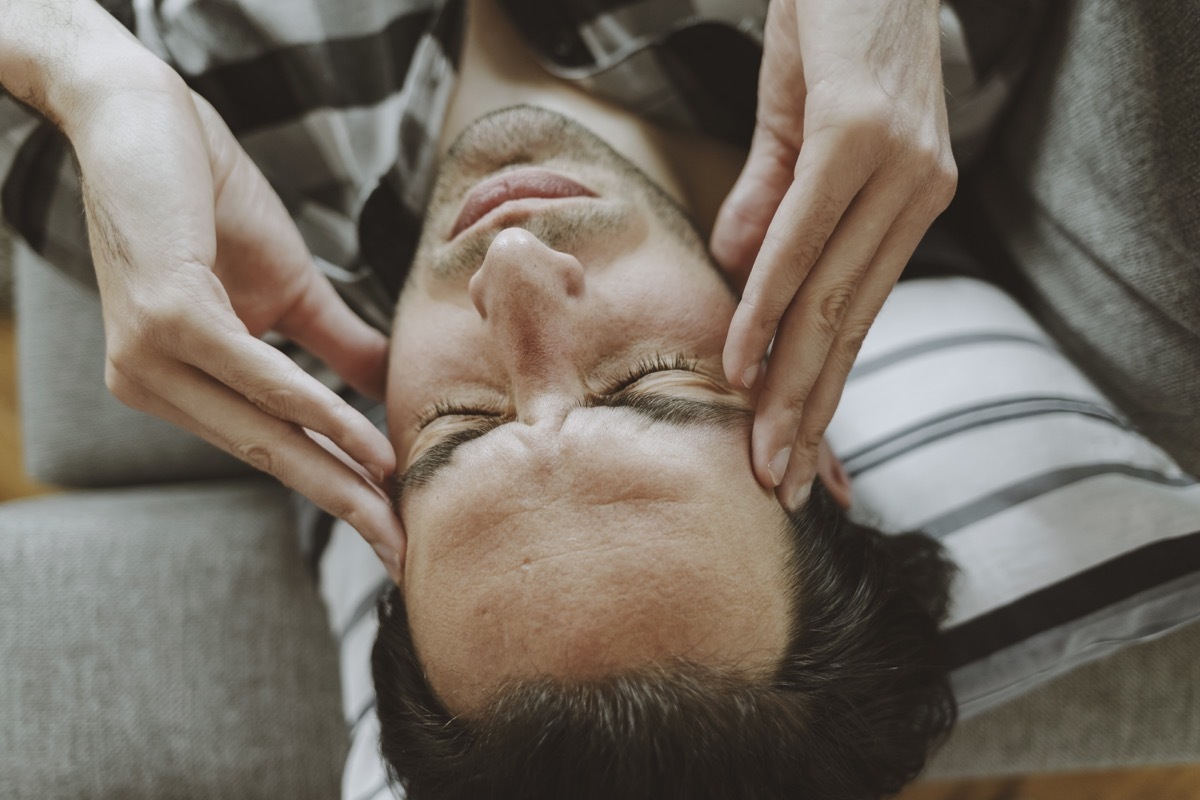 Feeling Stressed. Frustrated Handsome Young Man Touching His Head and Keeping Eyes Closed on the Couch at Home While Having Headache