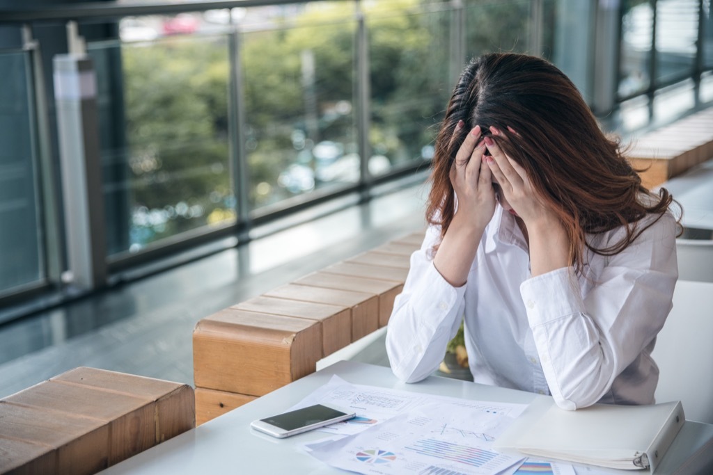 woman at desk with head in hands