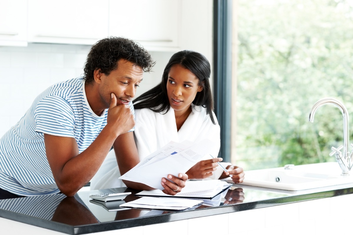 Portrait of worried young couple reading financial documents in kitchen