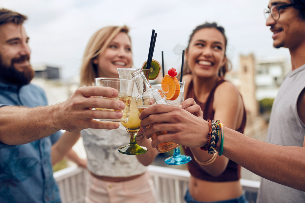 group of happy young friends drinking and toasting glasses