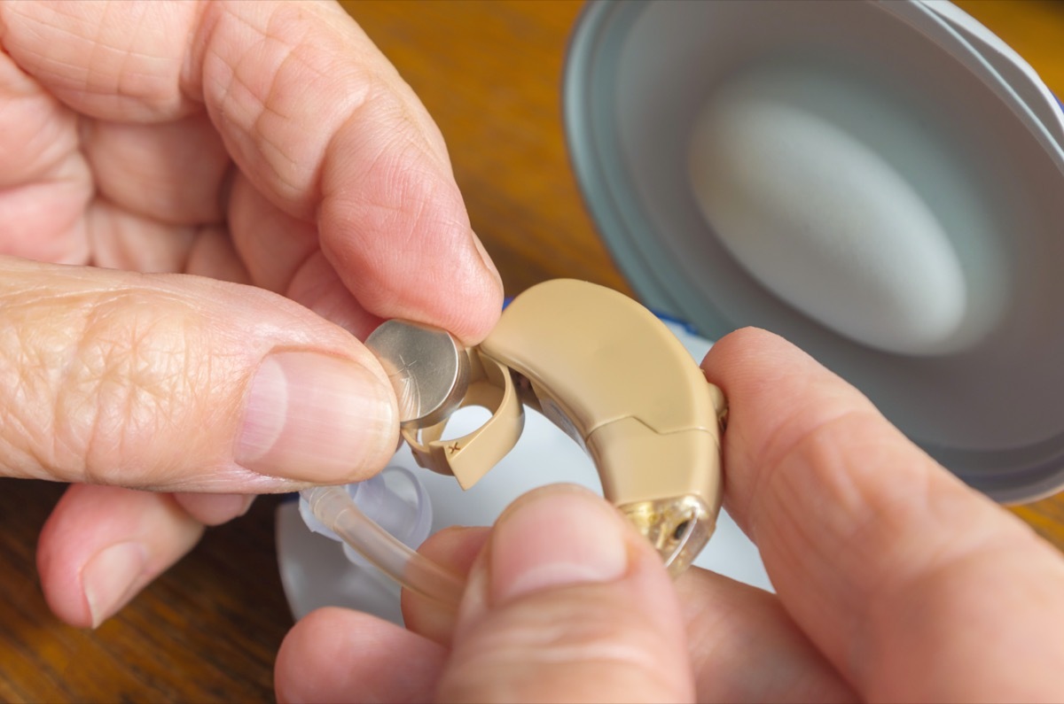 Elderly woman changes the battery in the hearing aid