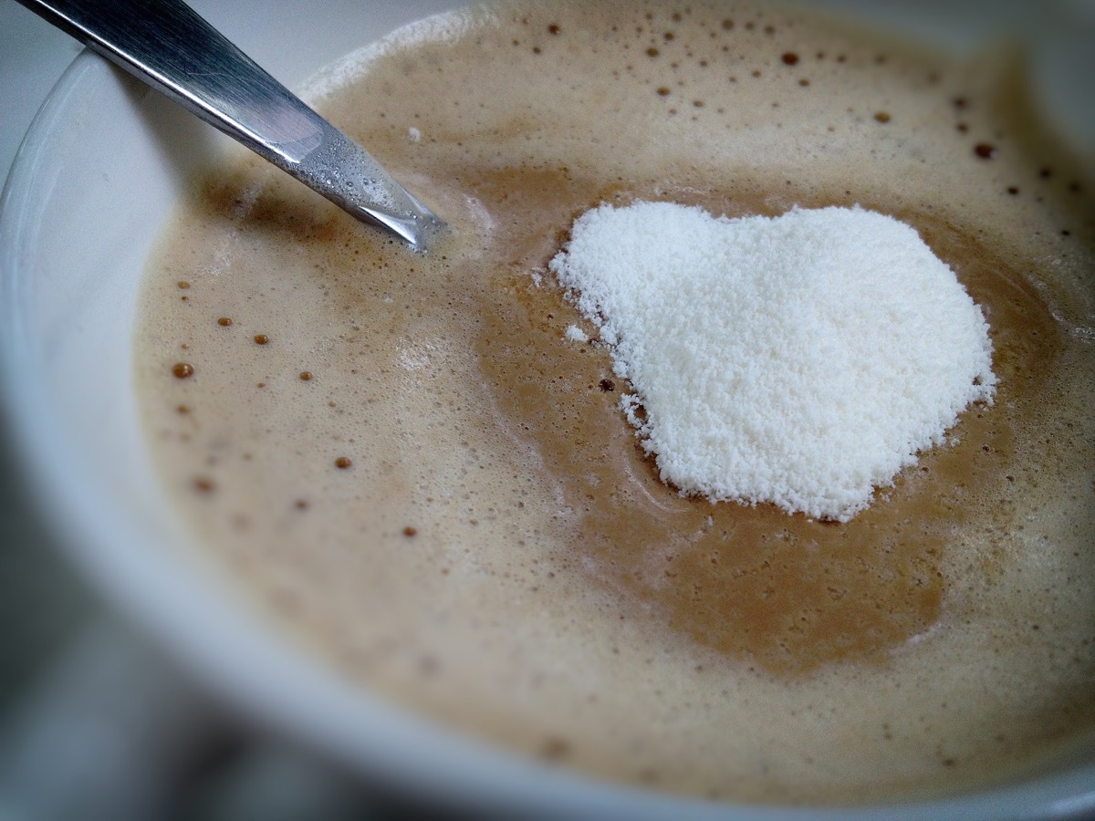 spoon with non-dairy or powdered coffee creamer being stirred into cup