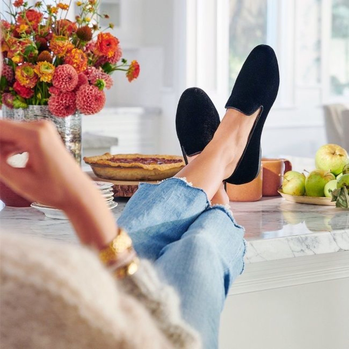 woman on couch wearing black velvet slippers