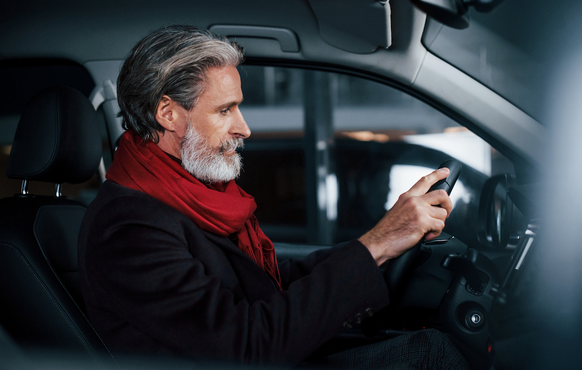 Side view of senior man with grey hair in a car.