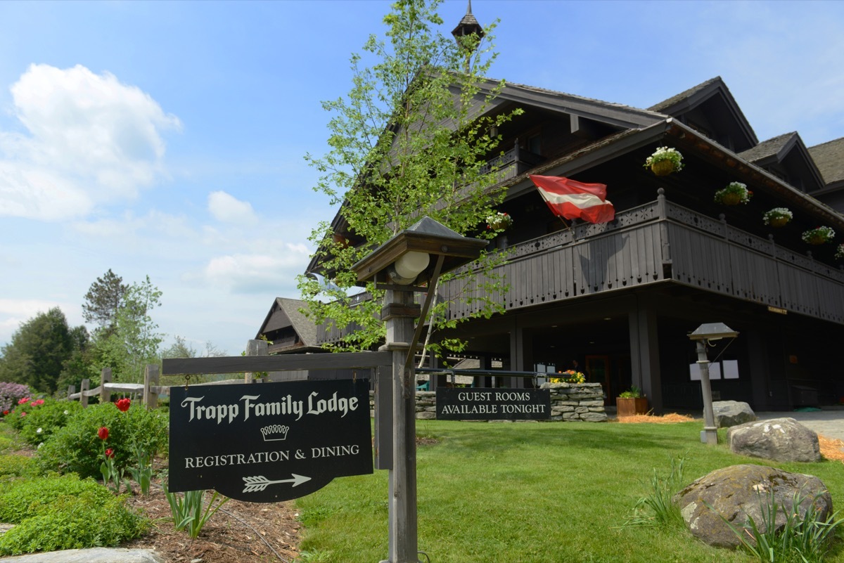 Trapp Family Lodge sits behind inn sign on a sunny day, state fact about vermont