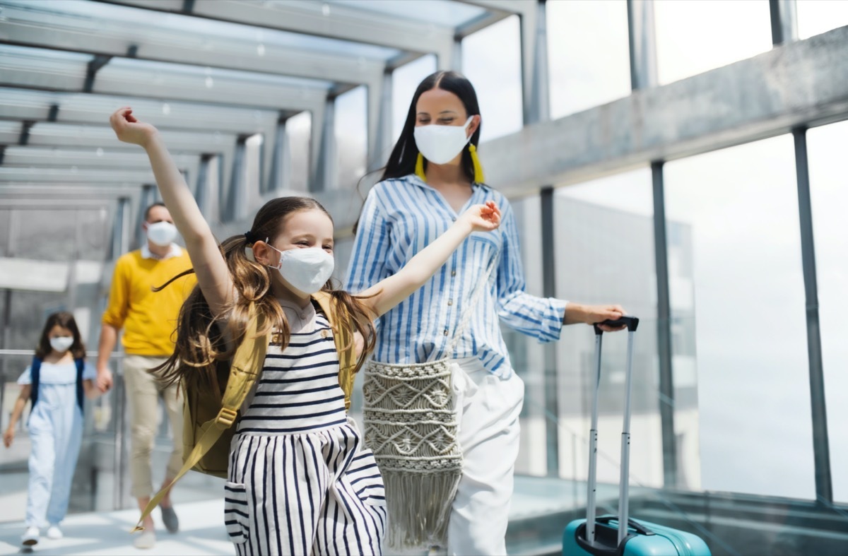 Family with two children going on holiday, wearing face masks at the airport.