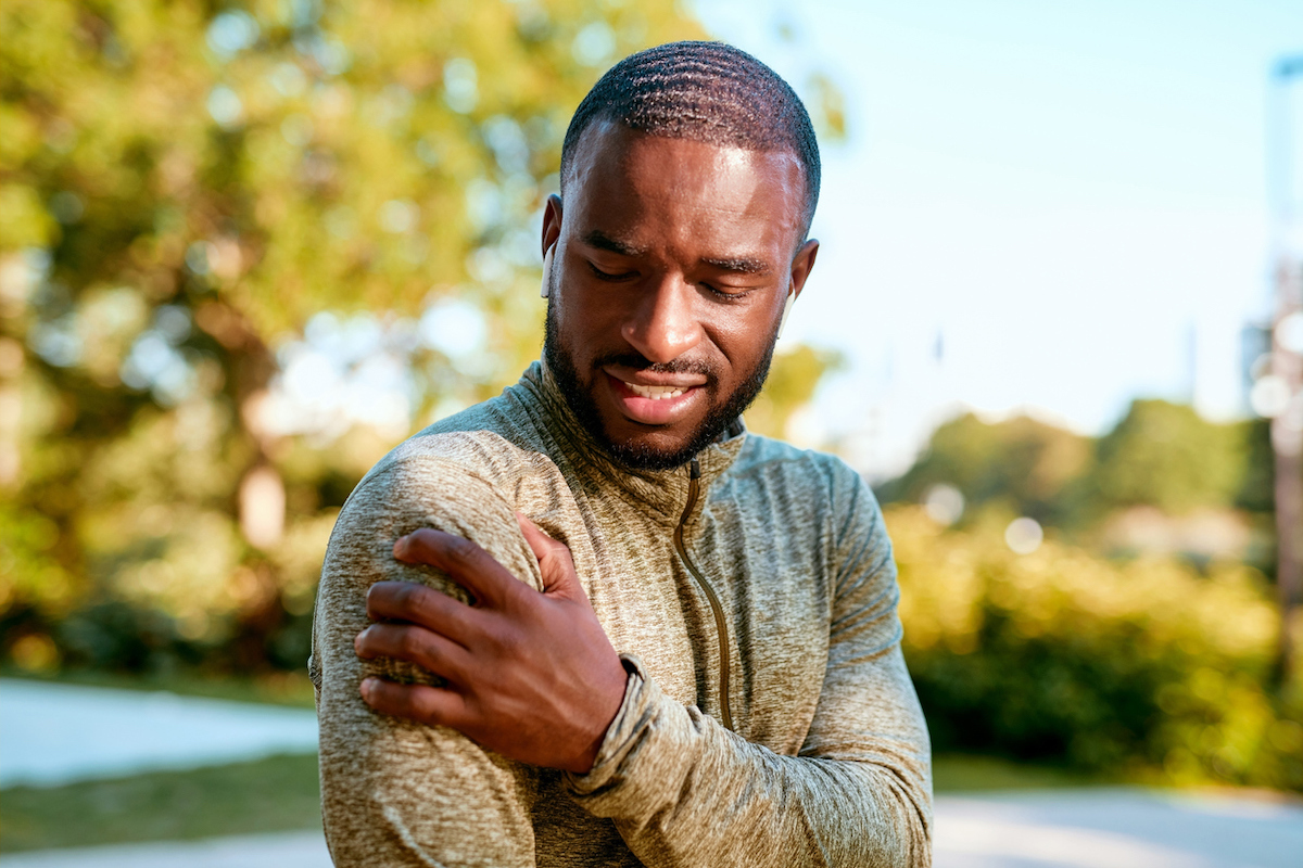 Young man grabbing upper arm in pain