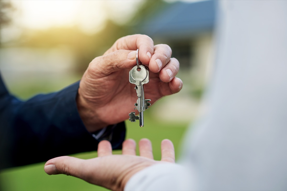 two hands handing over a key for property