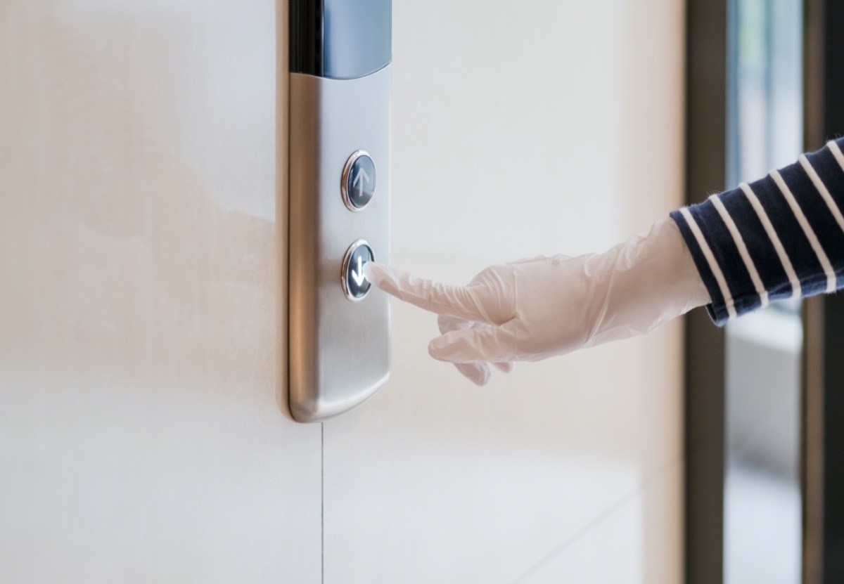 Hand press a button of elevator inside the building