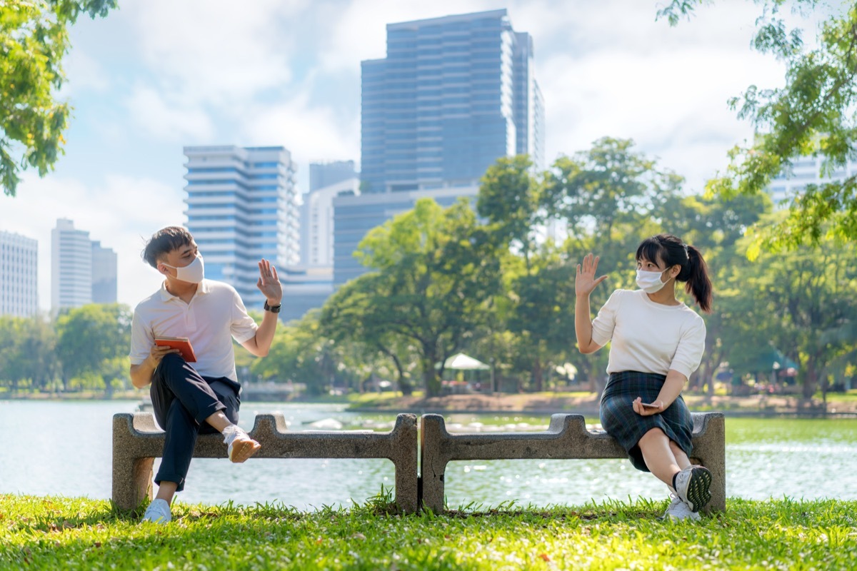 two people sitting on a bench in a park