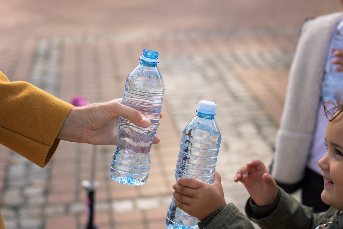 Close up of mother and daughter toasting with water bottles.