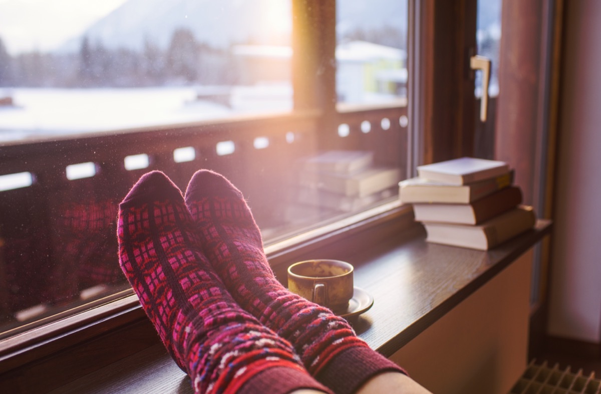 socks on a heater next to books and a cup of tea in a home in winter