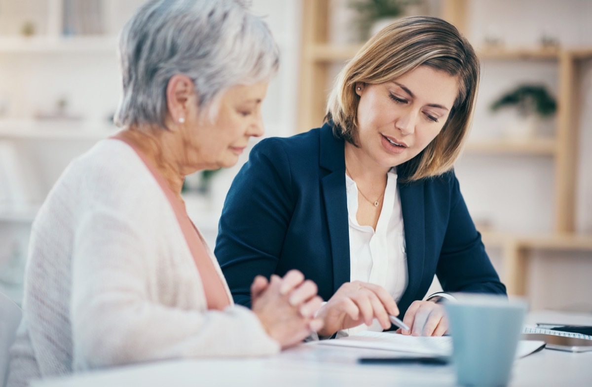 Financial advisor explaining and showing mature woman where to sign a document