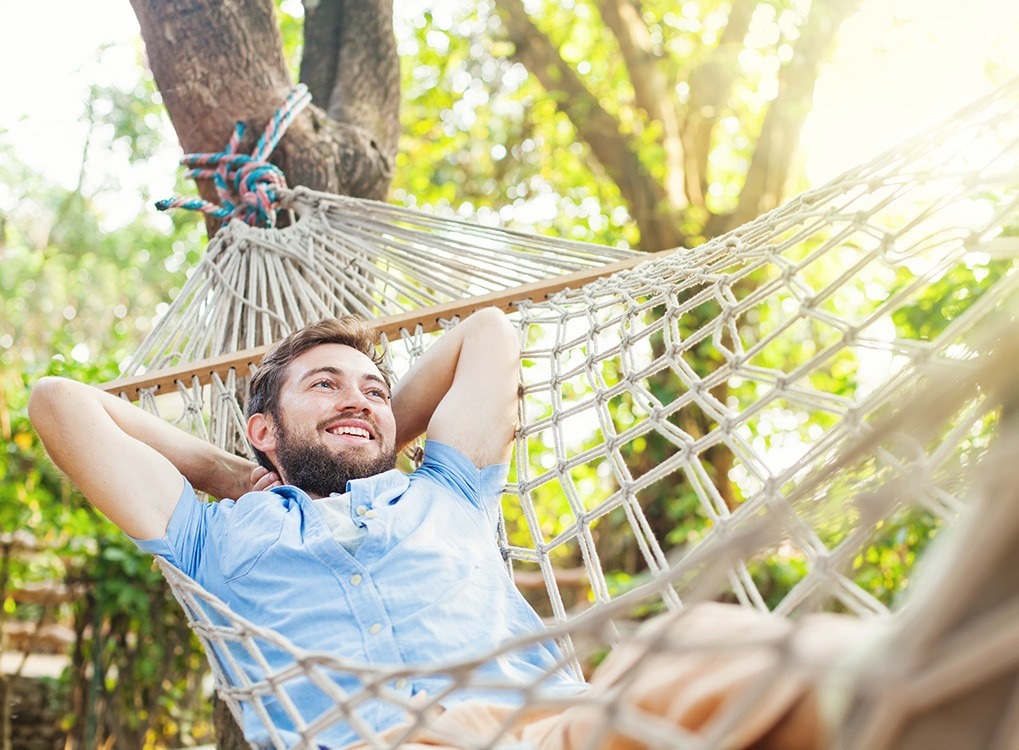 Young smiling man lounging in a hammock.