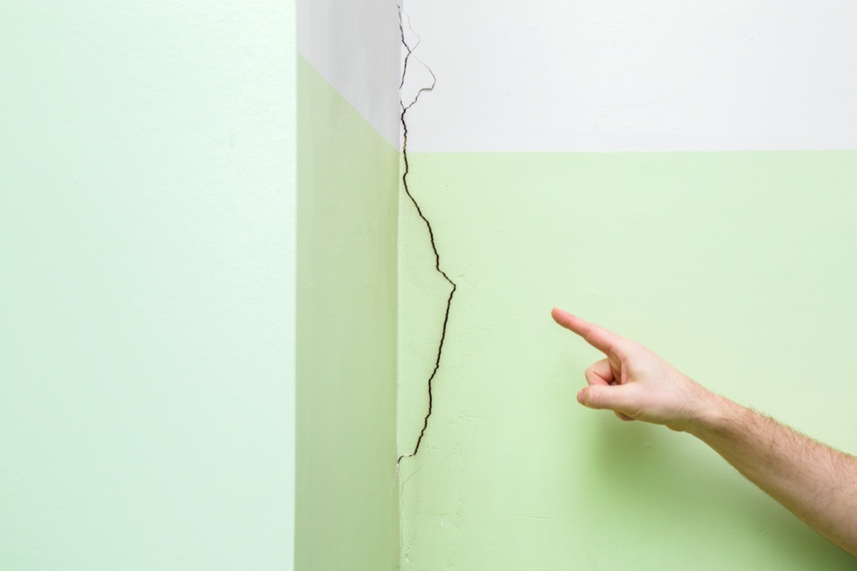 white hand pointed at cracked wall