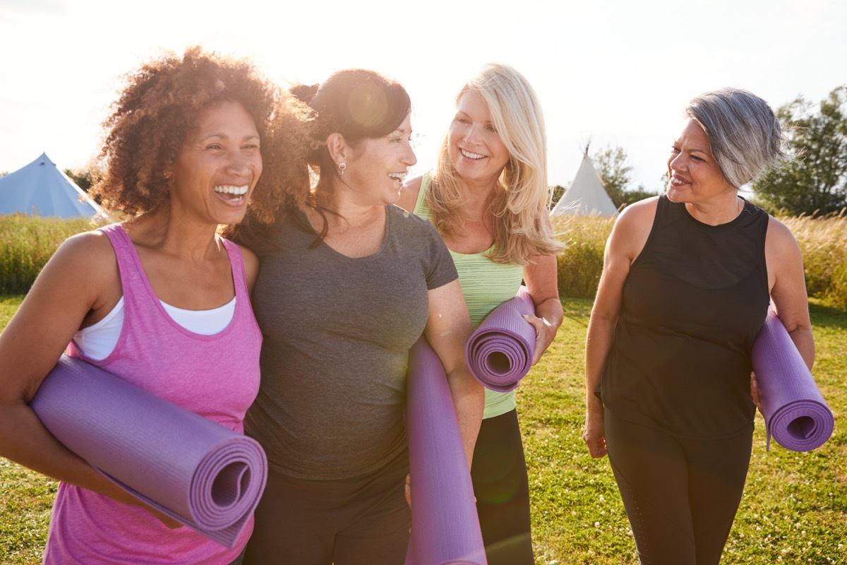 Older group of friends leaving yoga class with mats