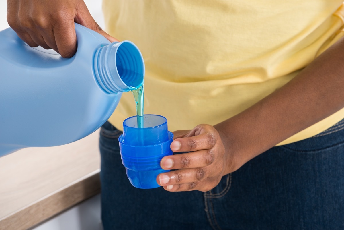 pouring laundry detergent in a cup