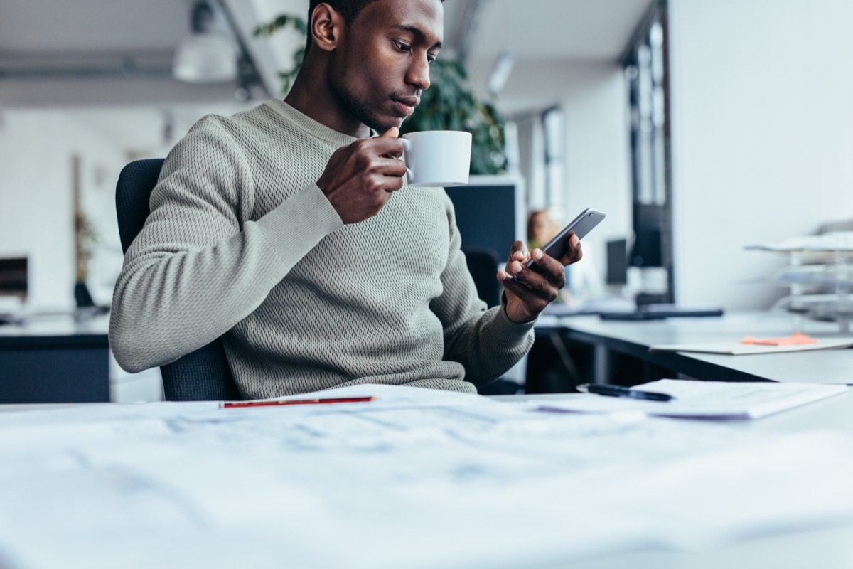 young man at office looking at smartphone