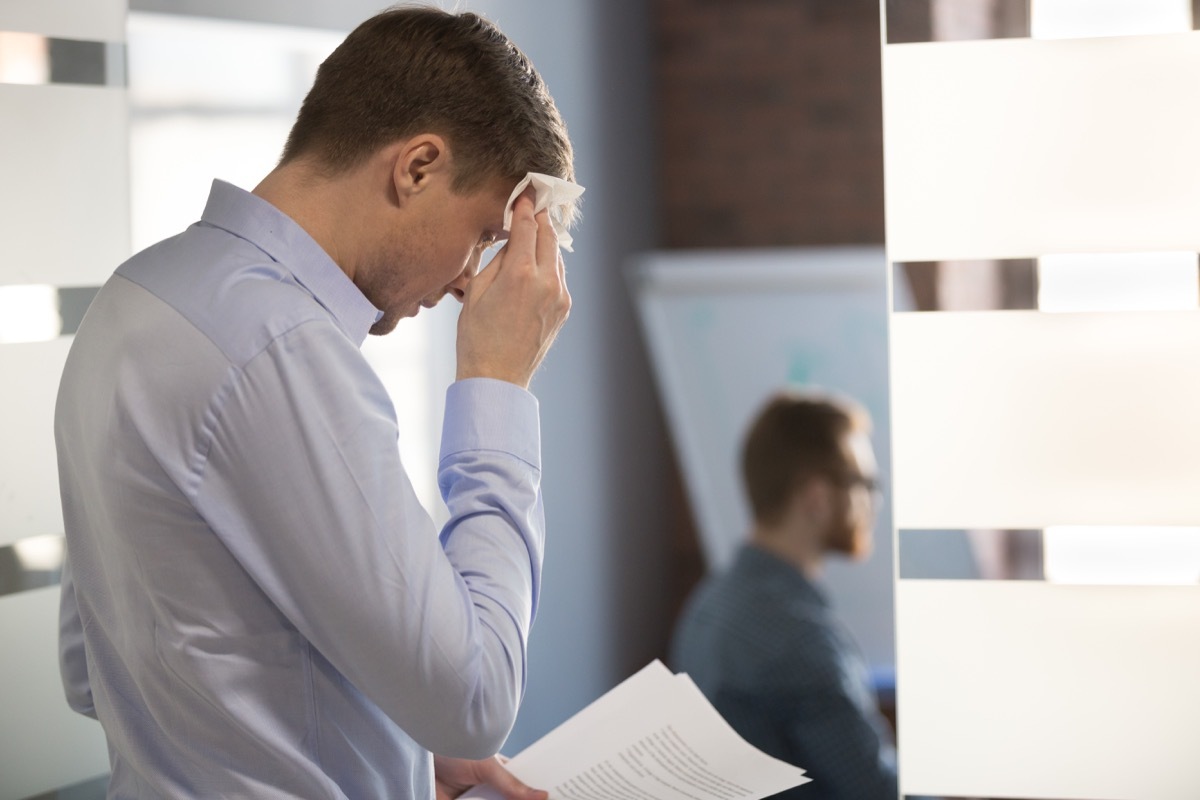 Nervous sweaty business man speaker preparing speech afraid of public speaking wiping wet forehead with handkerchief feeling stressed or worried about sweating before important office performance